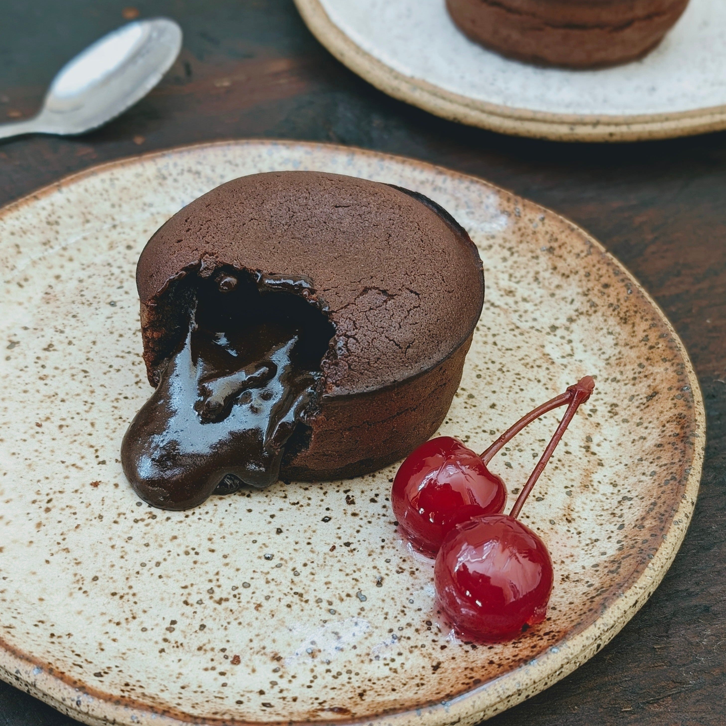 Chocolate lava cake with molten chocolate center and cherries on a plate