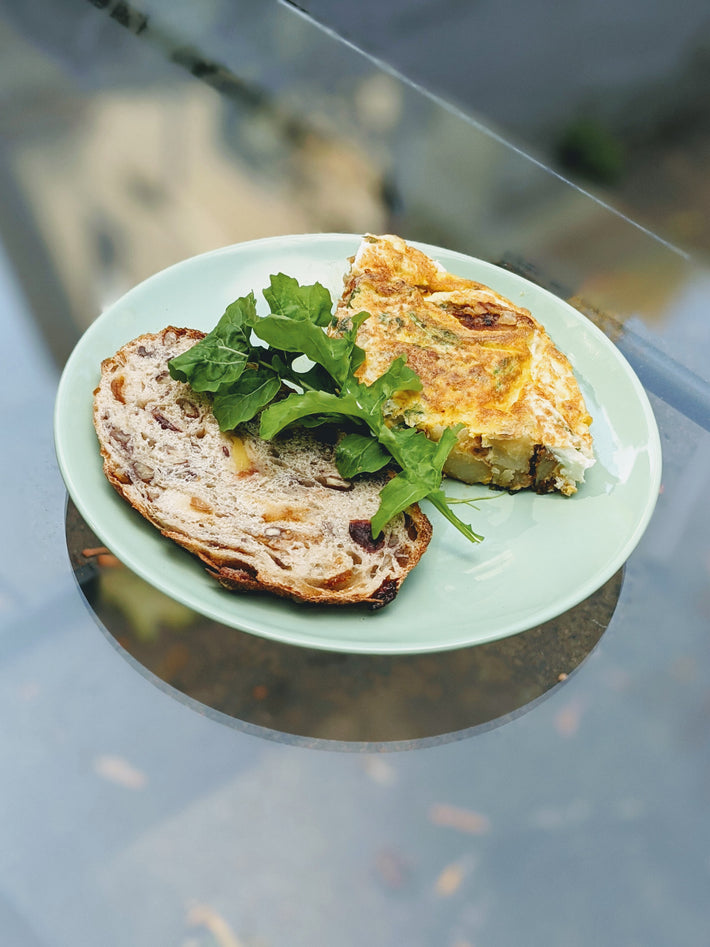 A slice of bread with nuts and a vegetable frittata on a green plate