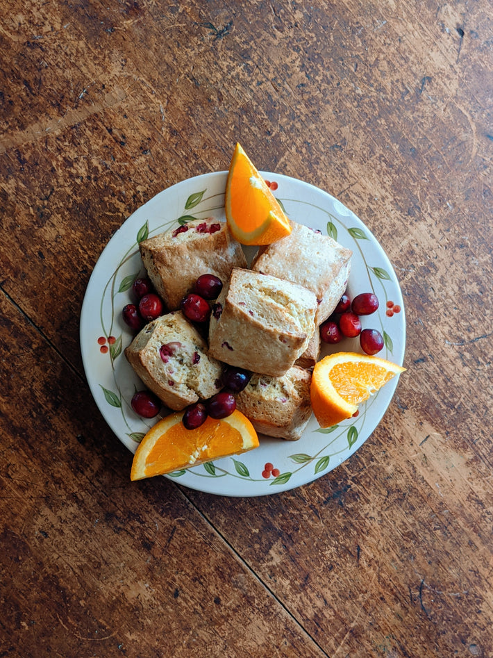Orange cranberry biscuits on a plate with orange slices and cranberries
