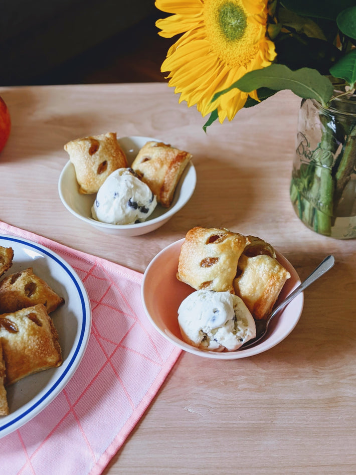 A bowl of pastries with ice cream and a flower arrangement in the background