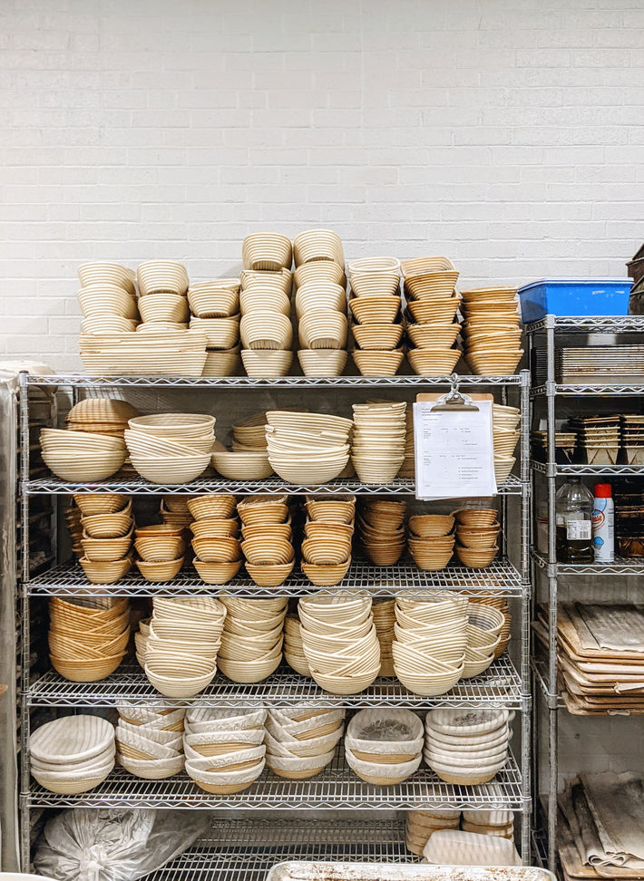 A shelf filled with various round proofing baskets used for bread making.