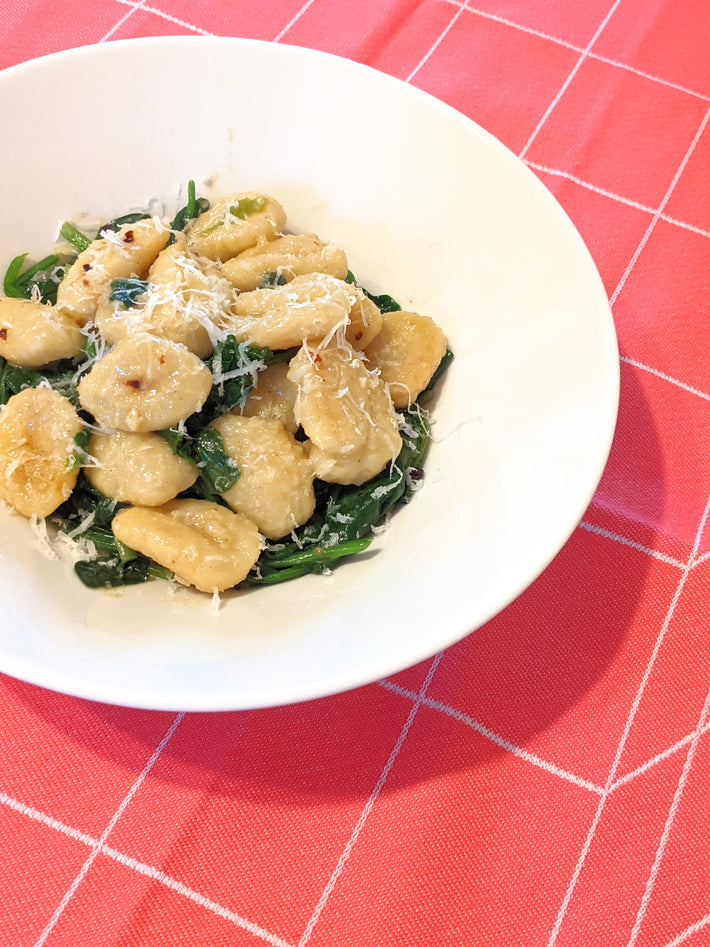 Potato Gnocchi served with spinach and cheese on a white plate