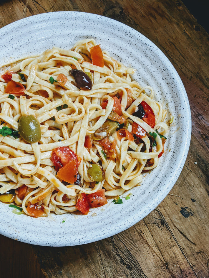 Plate of Tonnarelli pasta with tomatoes and olives