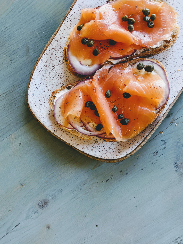 Two slices of bread topped with smoked salmon, red onion, and capers.