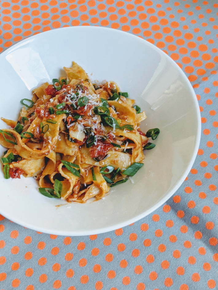 Bowl of Wildgrain Fettuccine topped with green onions and cheese