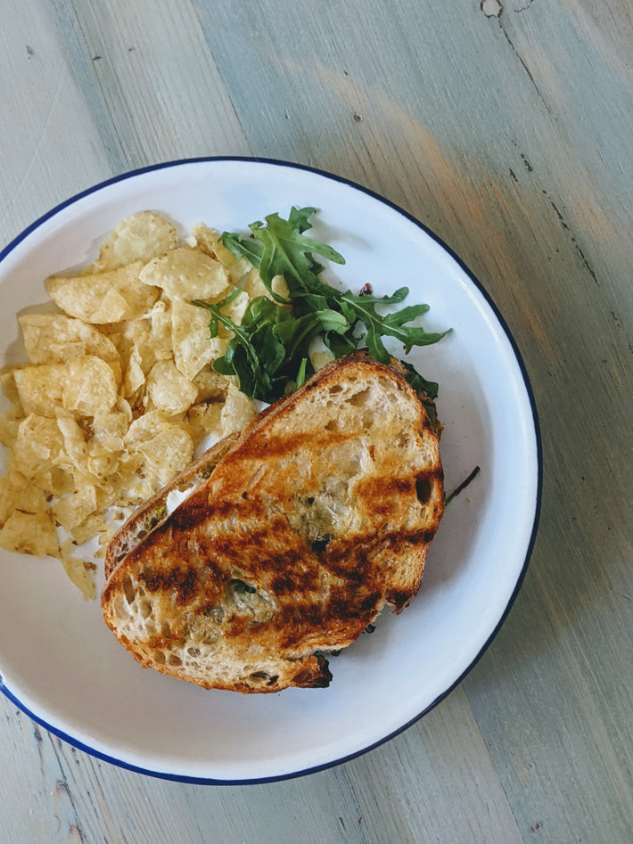Grilled sandwich with chips and arugula on a plate