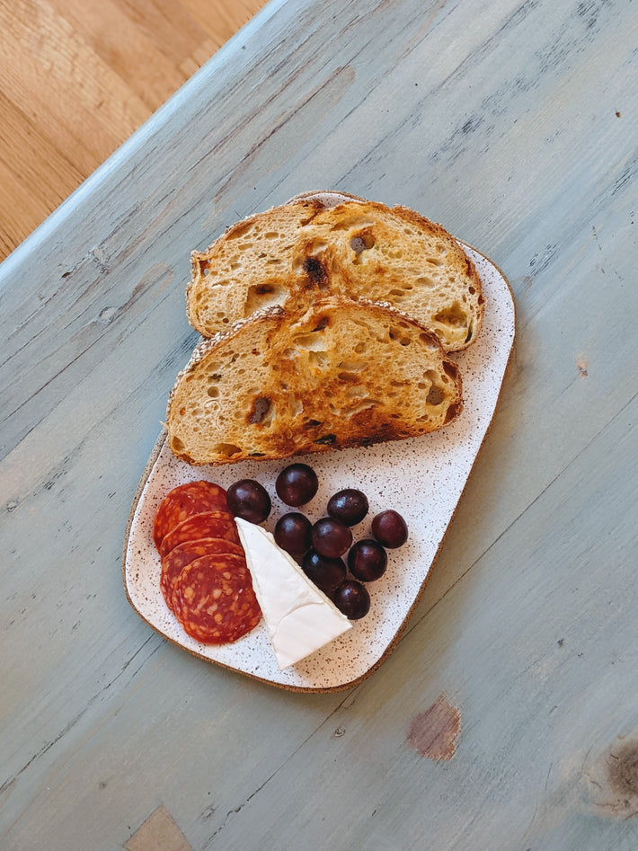 Sourdough bread slices with salami, grapes, and cheese on a plate