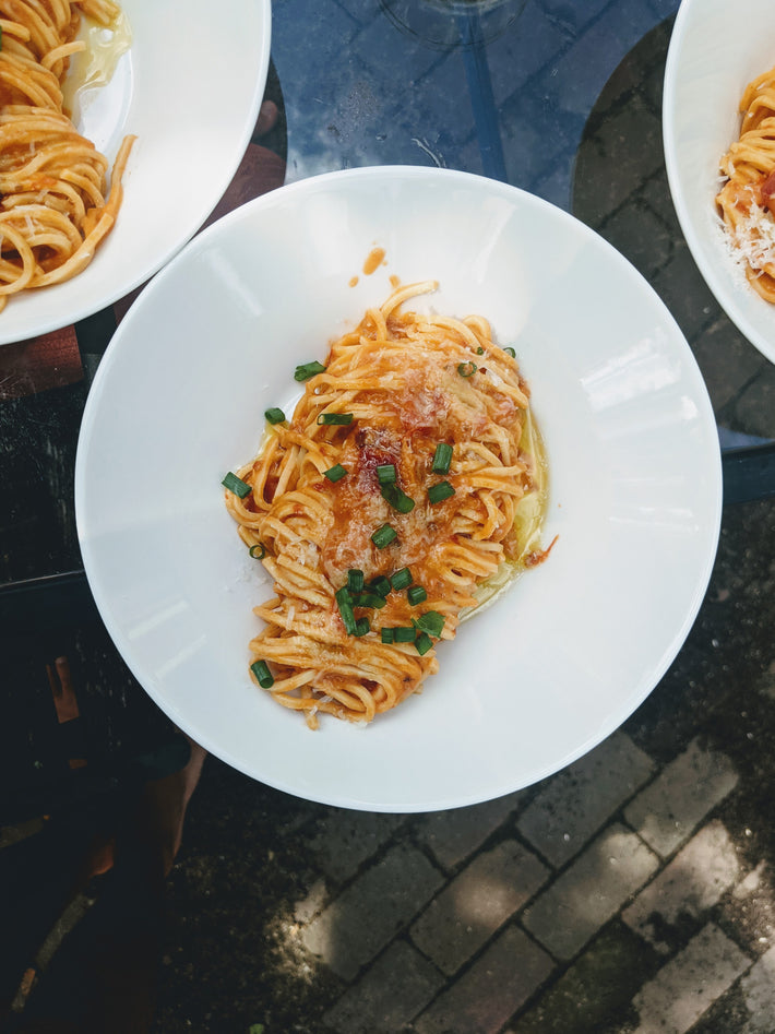 Plate of cooked pasta topped with cheese and green onions
