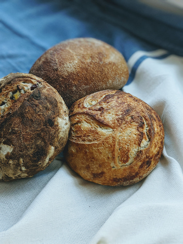 Three artisanal sourdough loaves on a cloth background