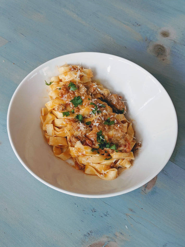 Fettuccine pasta with sauce and garnishes in a white bowl