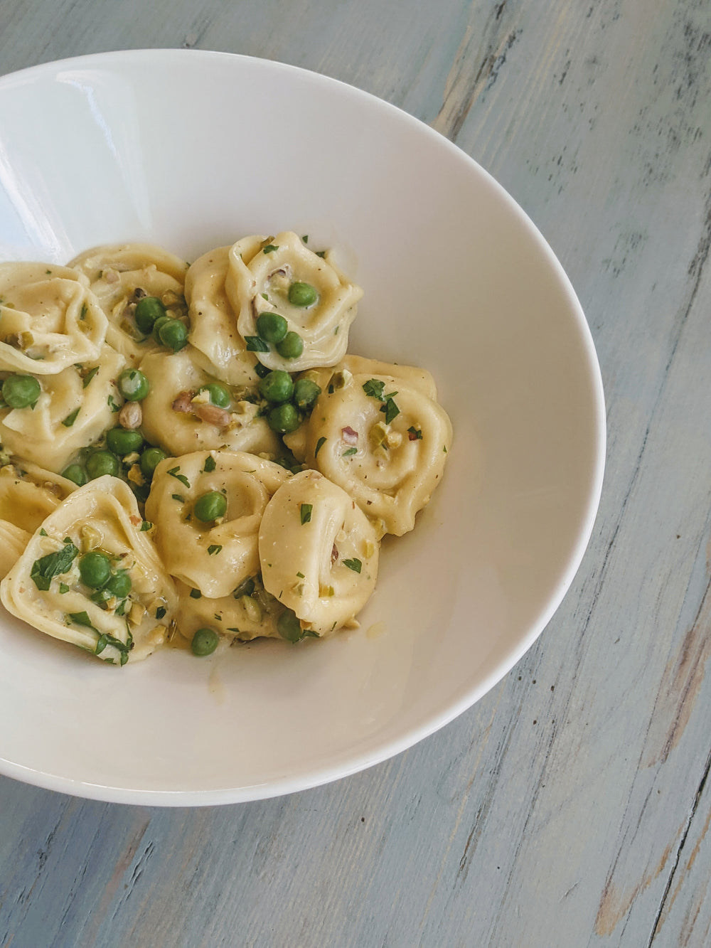 Cheese Tortellini with peas in a white bowl