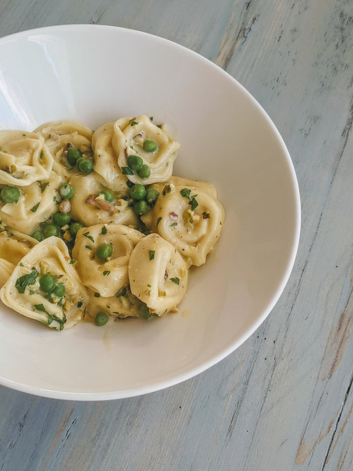 Cheese Tortellini with peas in a white bowl