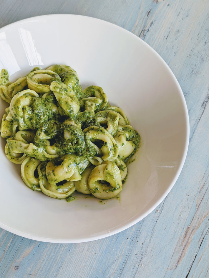 Cheese tortellini with pesto sauce in a white bowl