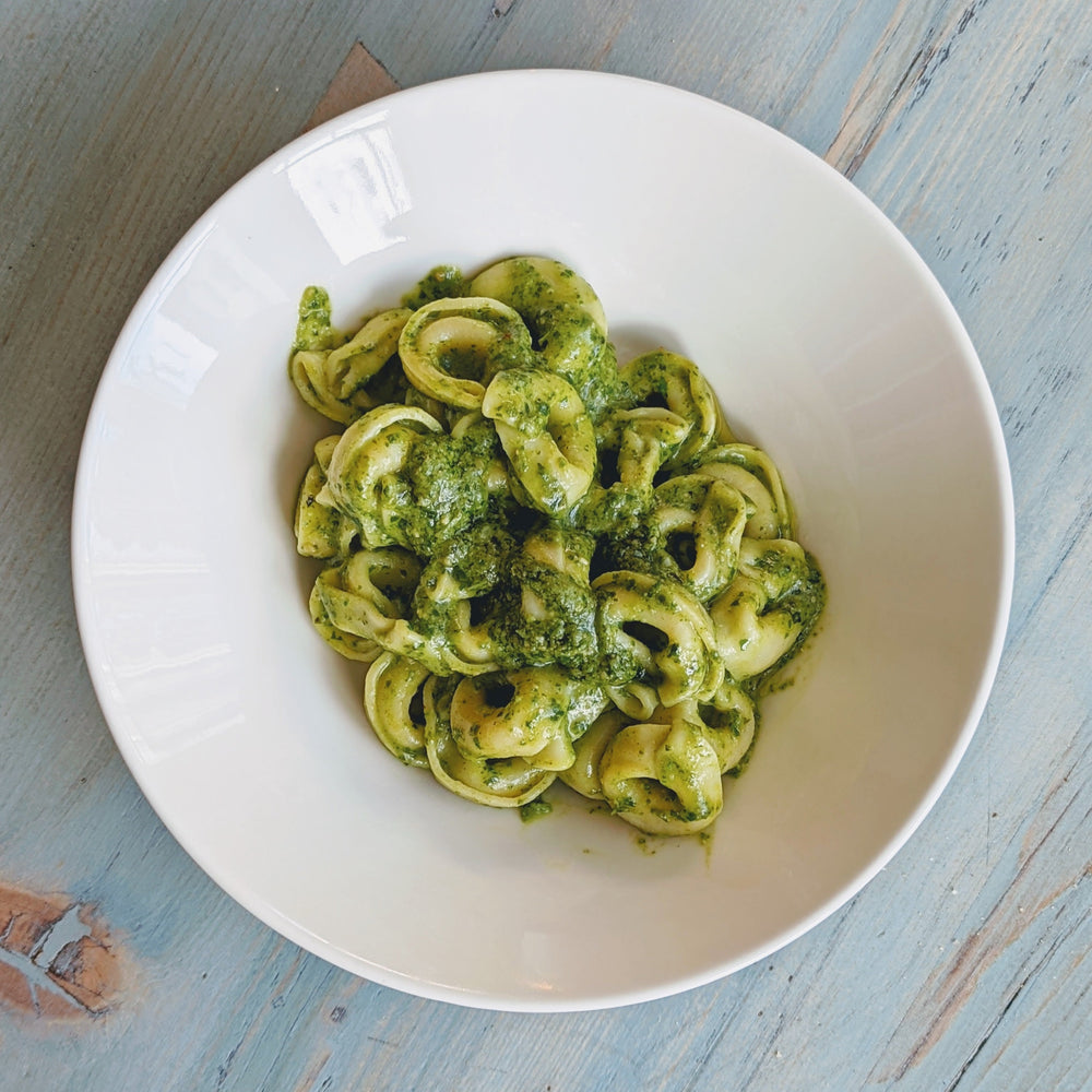 Pasta with pesto sauce in a white bowl