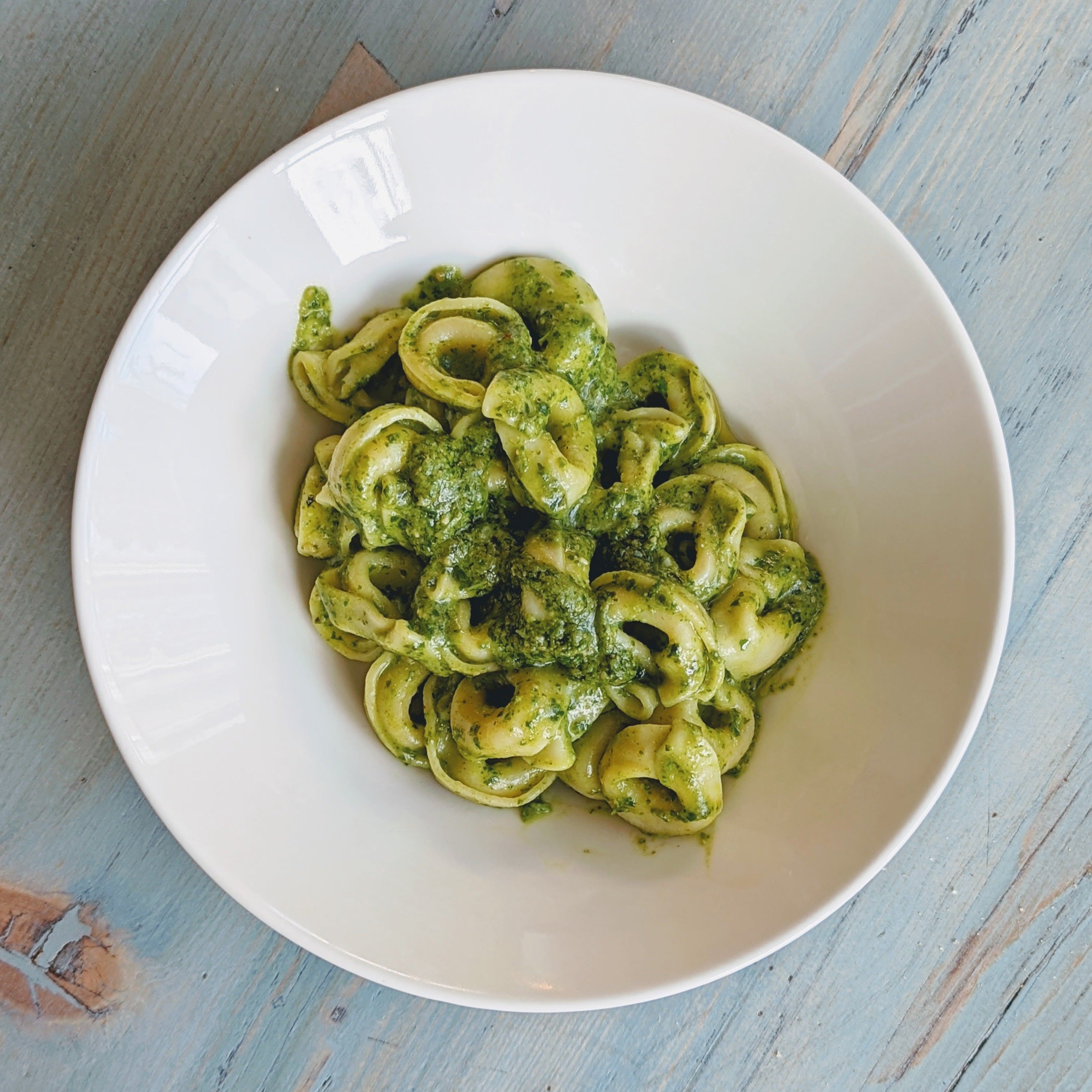Pasta with pesto sauce in a white bowl