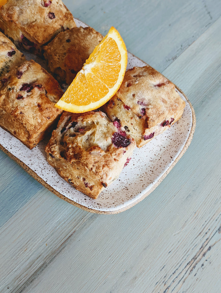 Orange cranberry biscuits on a plate with an orange slice