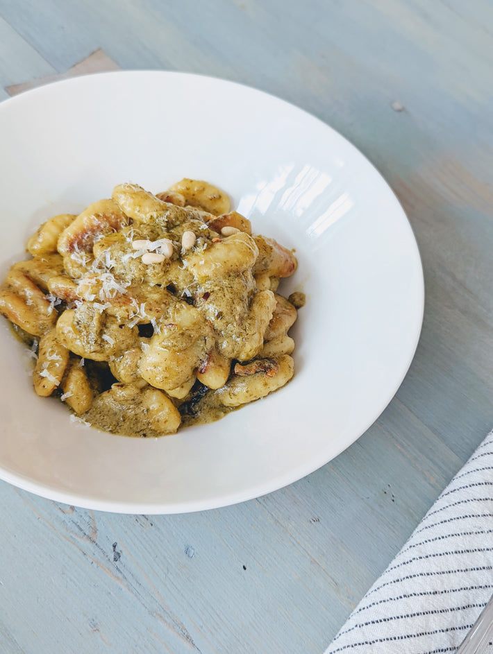 Potato Gnocchi with pesto sauce and cheese in a white bowl