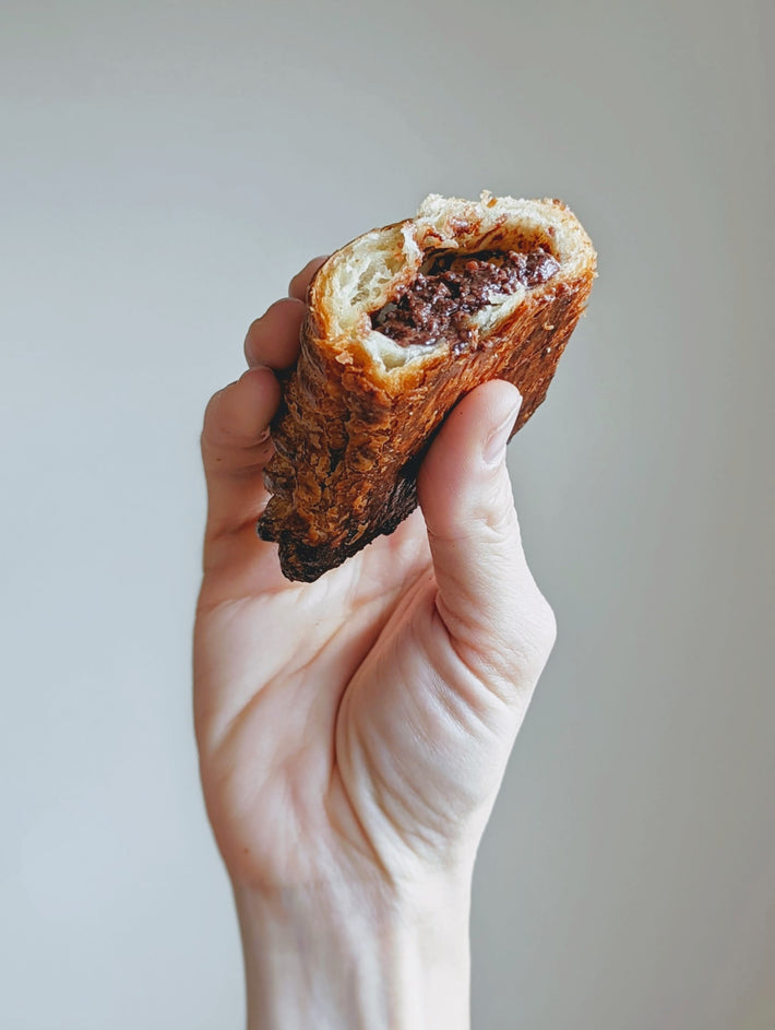 A person holding a chocolate-filled croissant
