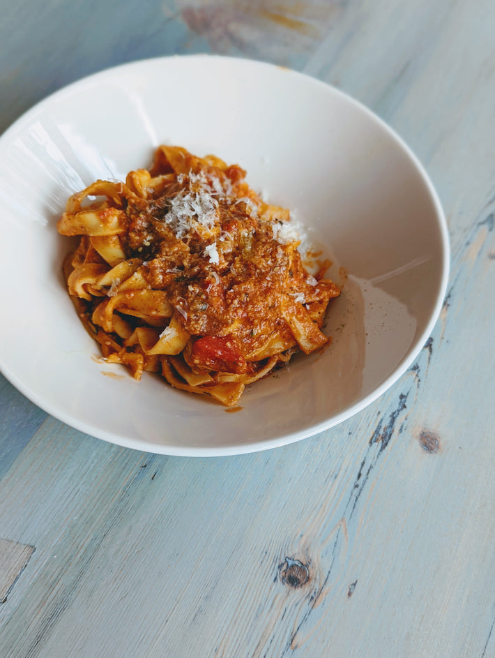 Fettuccine pasta with meat sauce and grated cheese in a white bowl