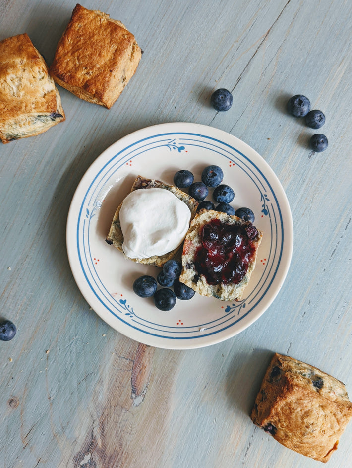 Blueberry biscuits served with whipped cream and blueberries on a plate