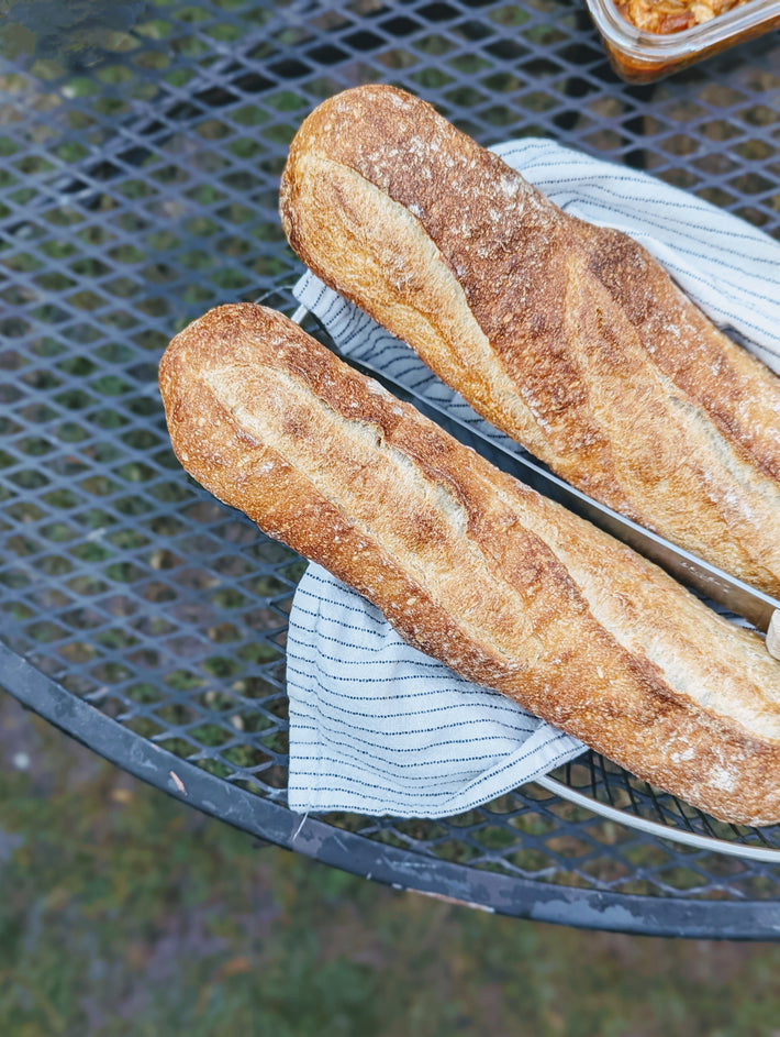 Two sourdough demi baguettes on a striped cloth