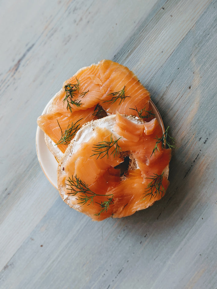 Wood-Fired Plain Bagels topped with smoked salmon and dill on a plate