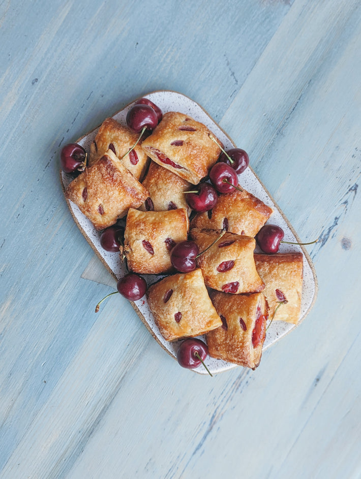 A platter of cherry pastries on a blue wooden table