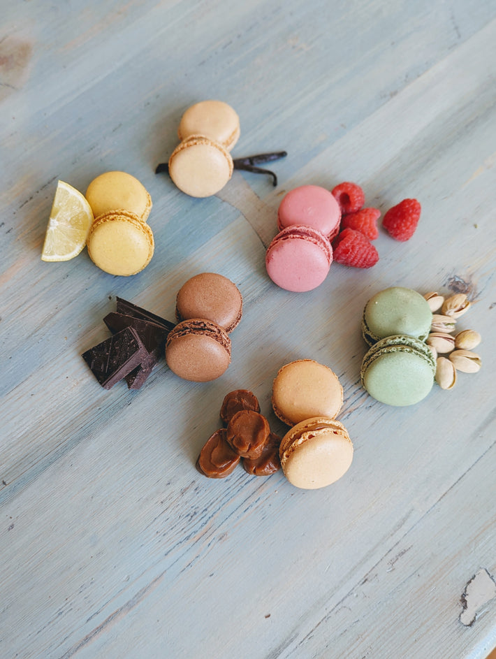 Assorted macarons in various colors with toppings on a wooden surface