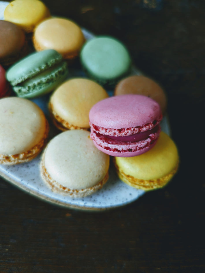 A plate of colorful macarons including pink, green, yellow, and beige.