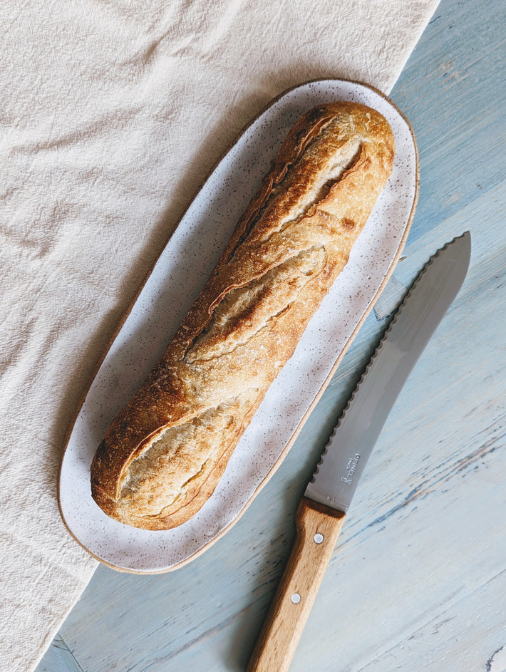 Sourdough Demi Baguette on a cutting board with a knife