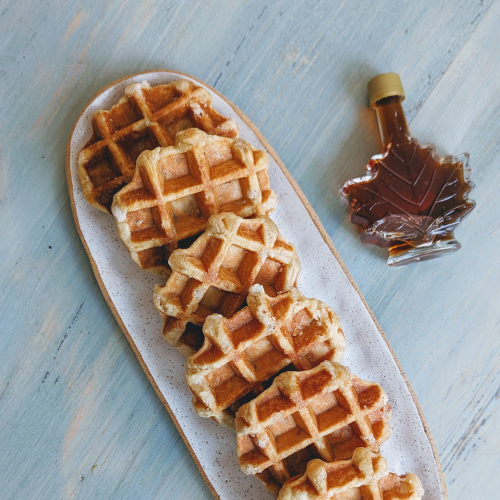Six Maple Belgian Waffles on a plate with a maple syrup bottle