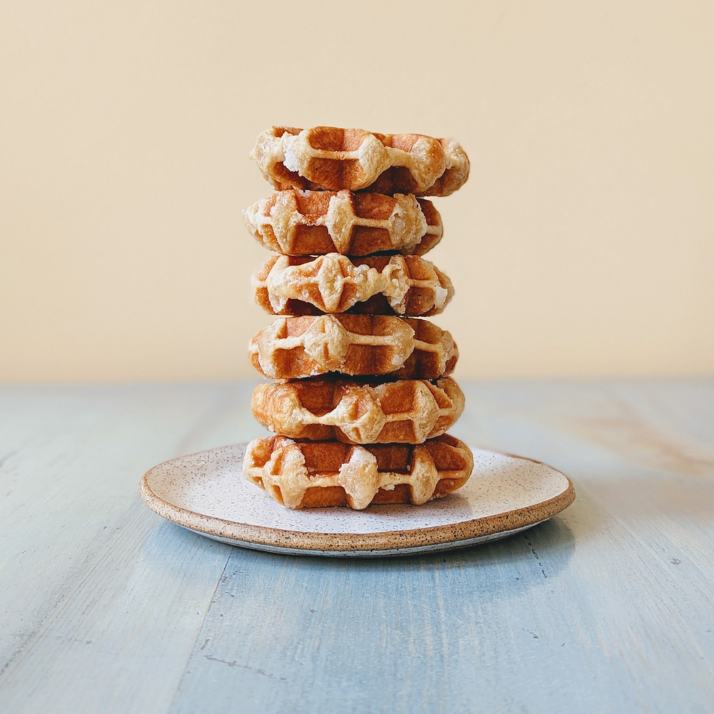 Stack of six round Belgian-style waffles on a speckled plate