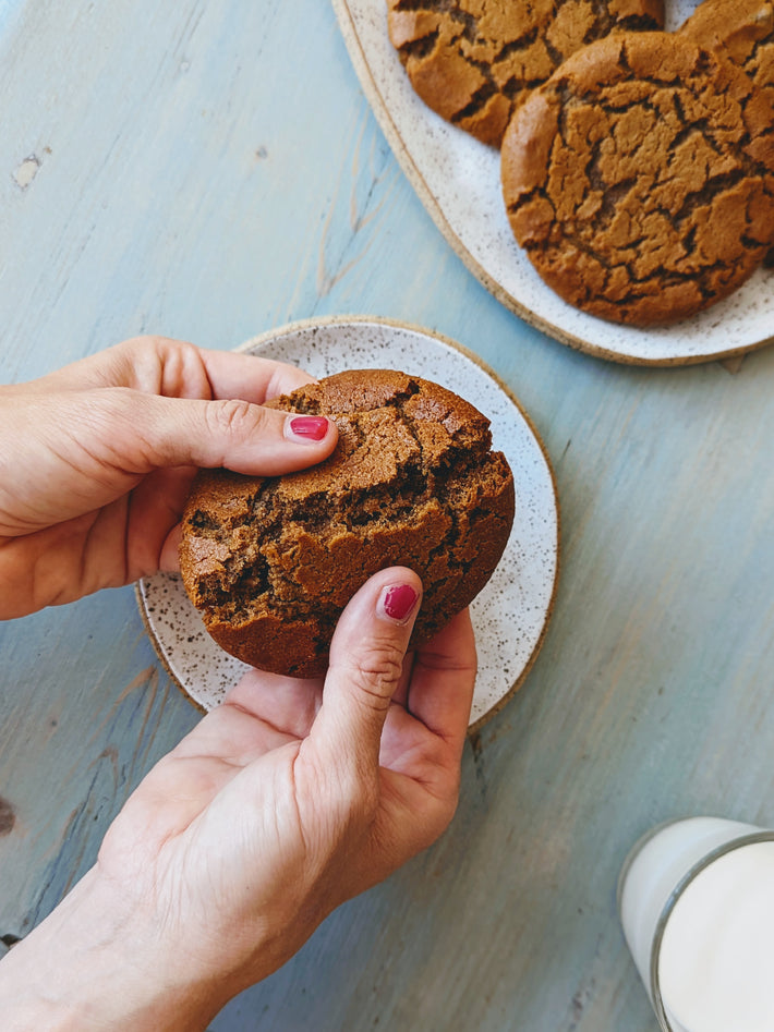 A person holding a Giant Ginger Molasses Cookie, breaking it apart to show texture.