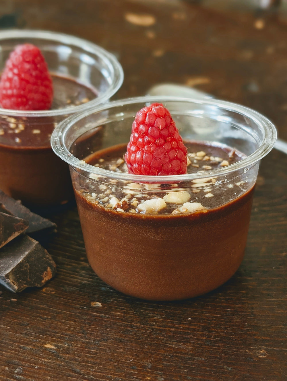 Chocolate mousse dessert topped with a raspberry in a clear jar