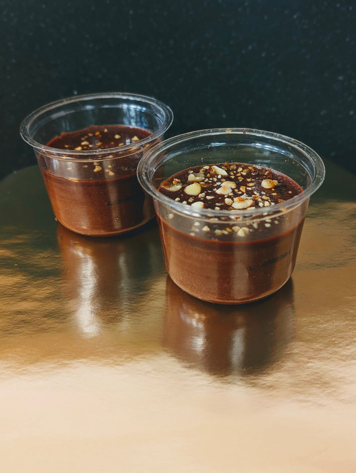 Two cups of chocolate mousse topped with crunchy hazelnuts
