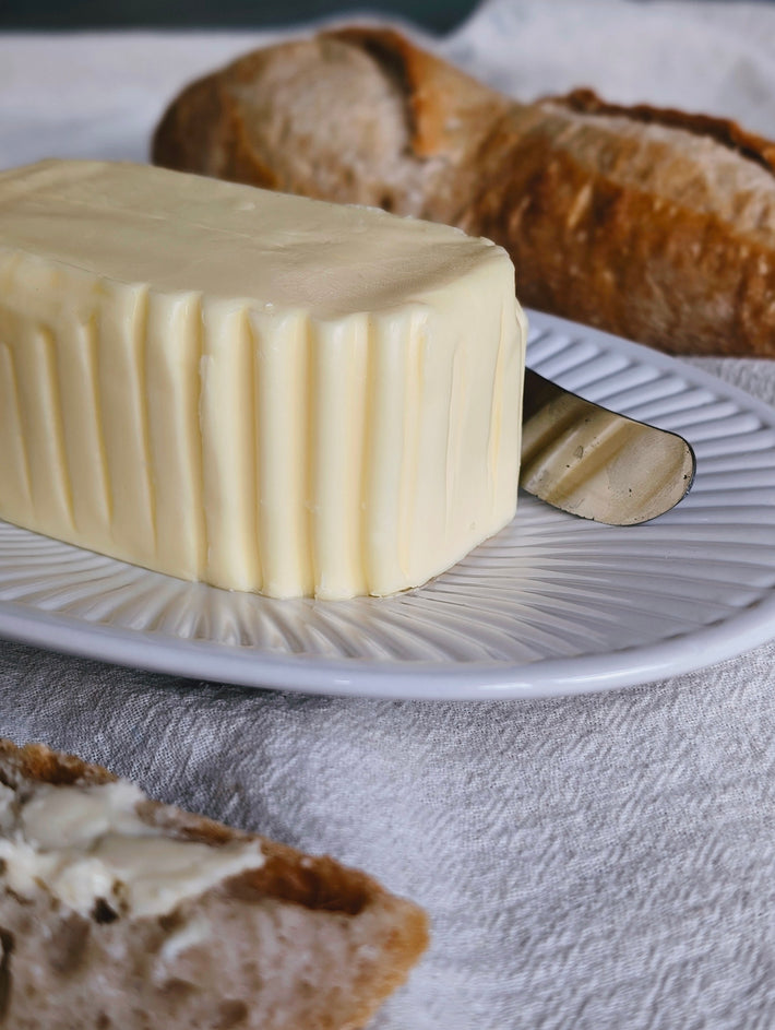 A block of Slow-Churned French Butter on a plate with bread