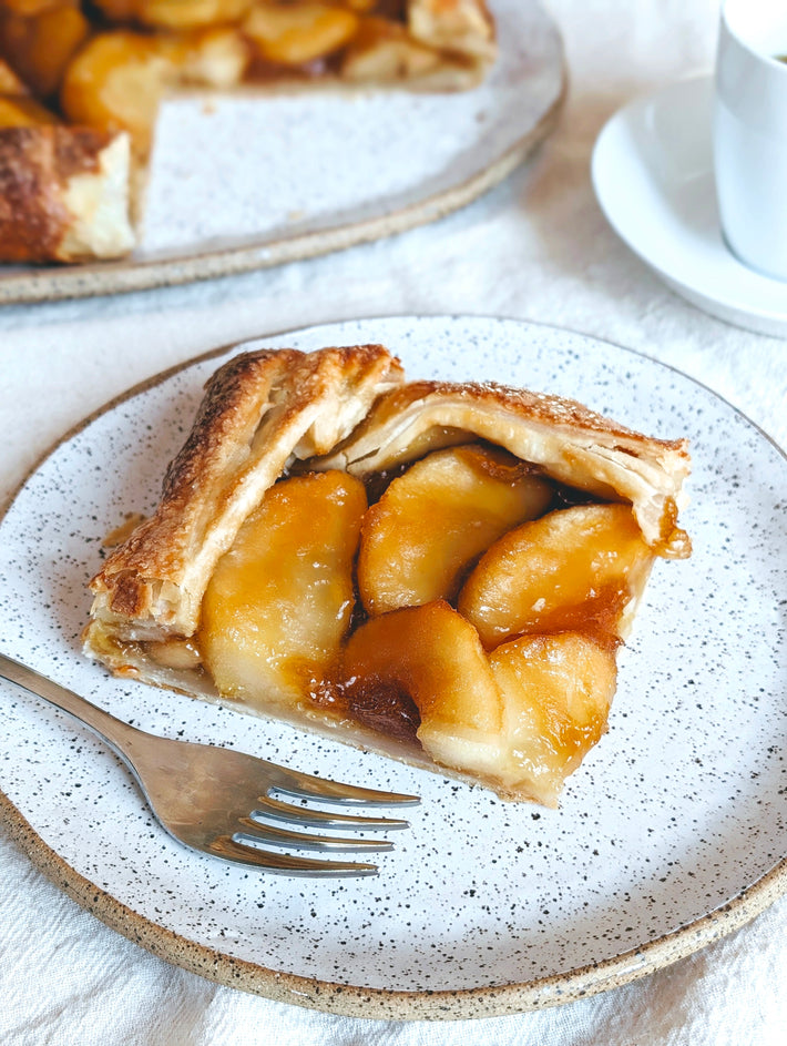 Slice of Apple Caramel Galette on a speckled plate with a fork beside it