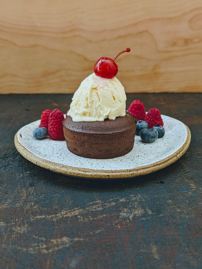 Chocolate lava cake topped with vanilla ice cream, raspberries, blueberries, and a cherry