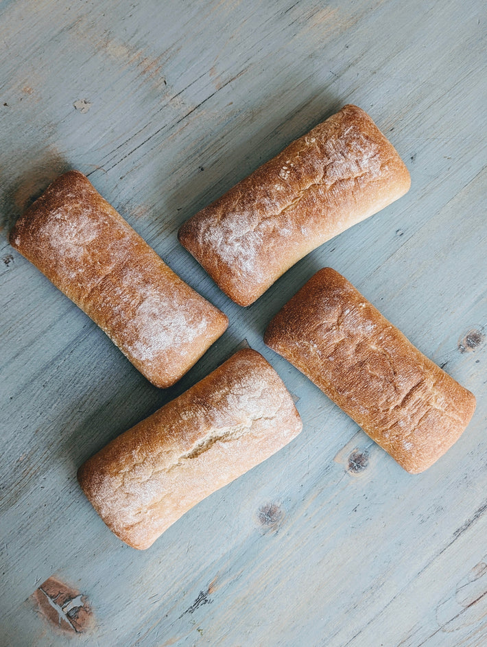 Four Slow-Fermented Ciabatta Sandwich Rolls on a wooden surface