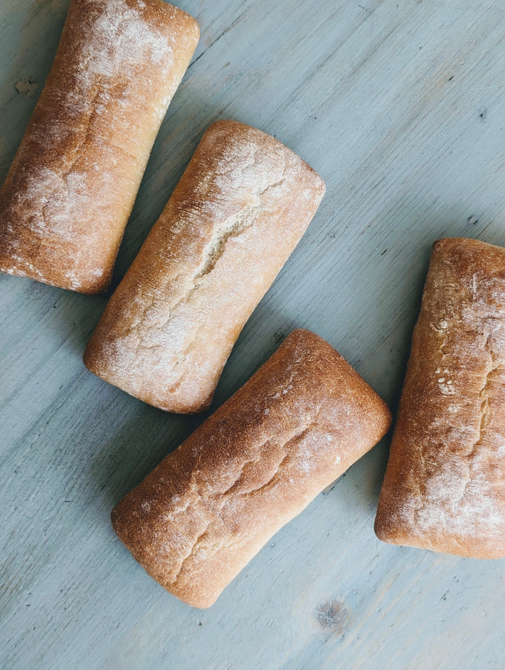 Four slow-fermented ciabatta rolls on a wooden surface