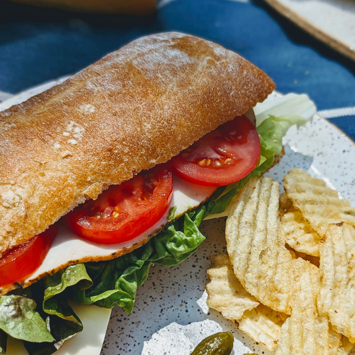 Slow-Fermented Ciabatta Sandwich with lettuce, tomato, and chips on the side