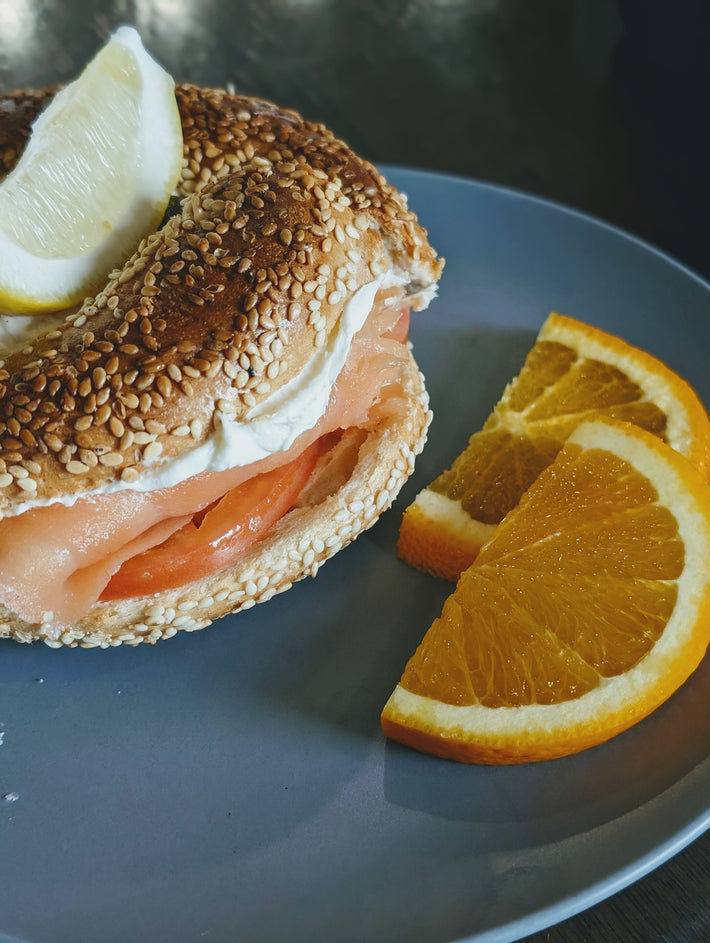 Sesame bagel with smoked salmon, cream cheese, and orange slices