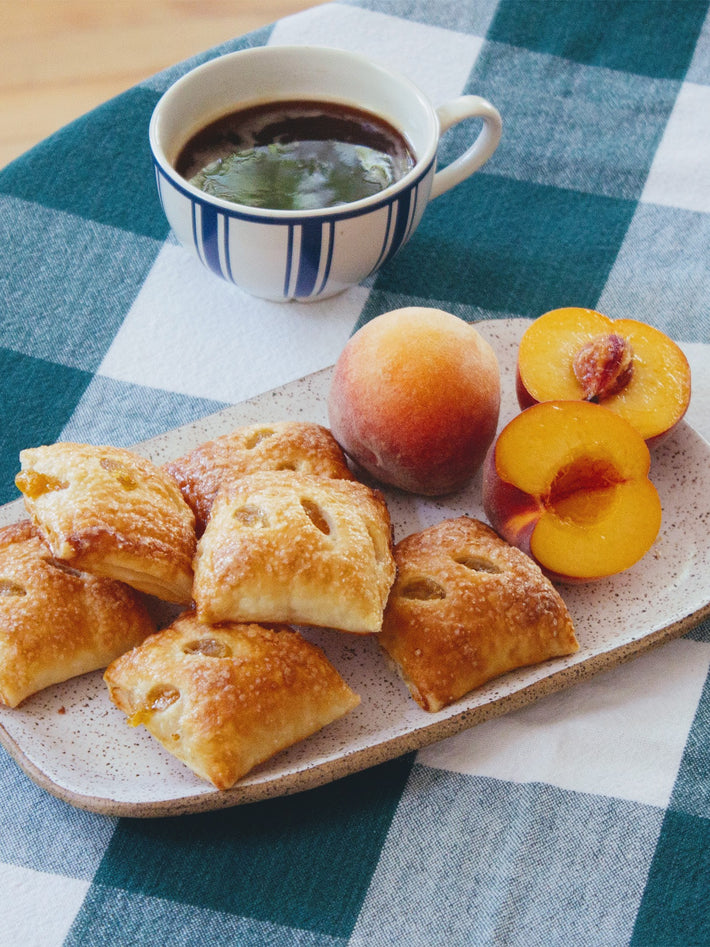 Peach Pie Bites on a plate with a cup of coffee and a peach