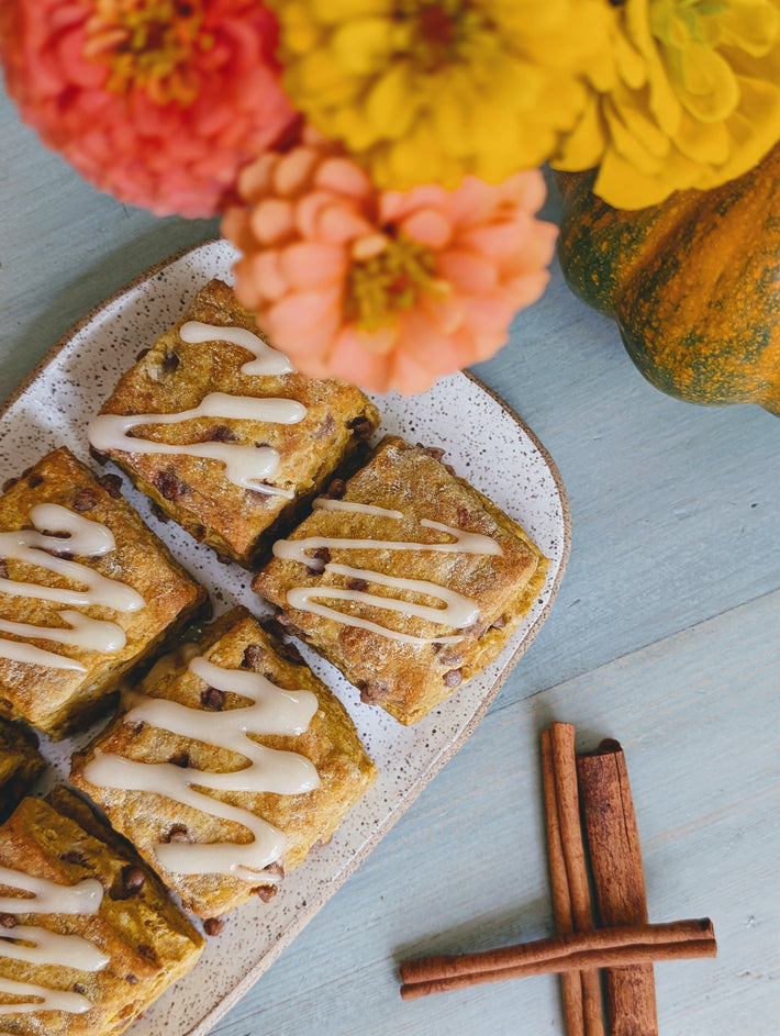 Pumpkin Cinnamon Biscuits drizzled with icing, surrounded by flowers and gourds.