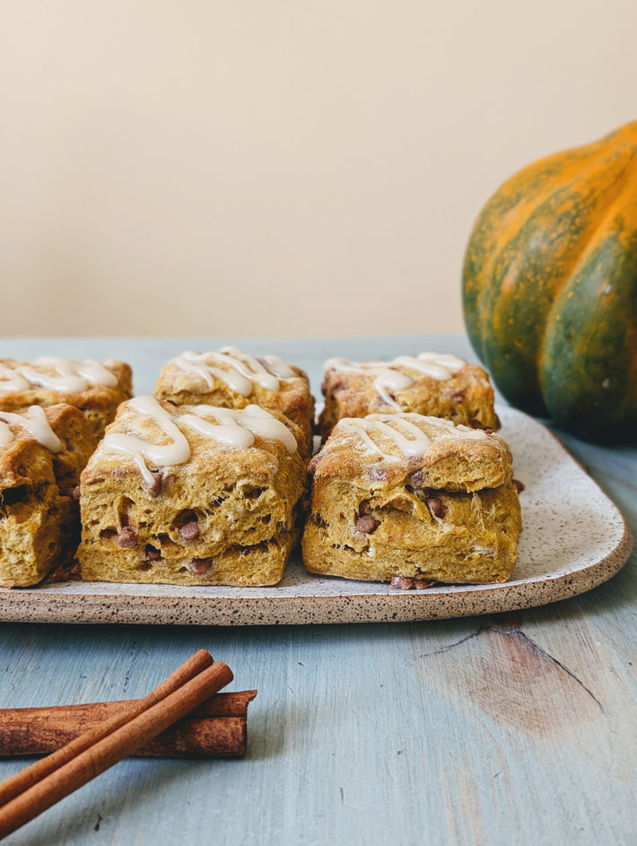 Pumpkin Cinnamon Biscuits on a plate with icing and cinnamon sticks.