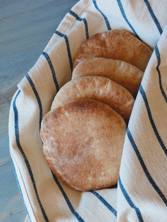 Slow-Fermented Artisanal Pita in a basket lined with a striped cloth.