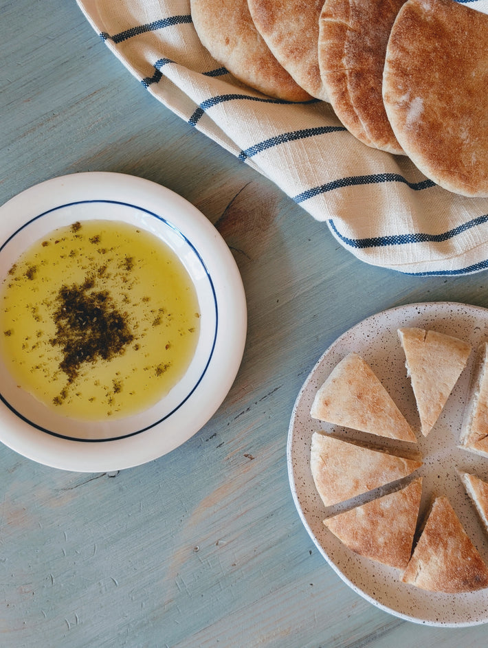 Sliced flatbread on a plate with olive oil and herbs.