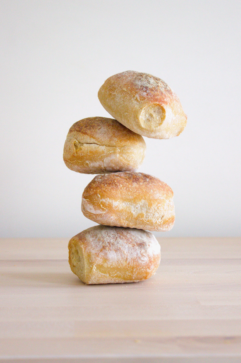 Four stacked sourdough rolls on a wooden surface