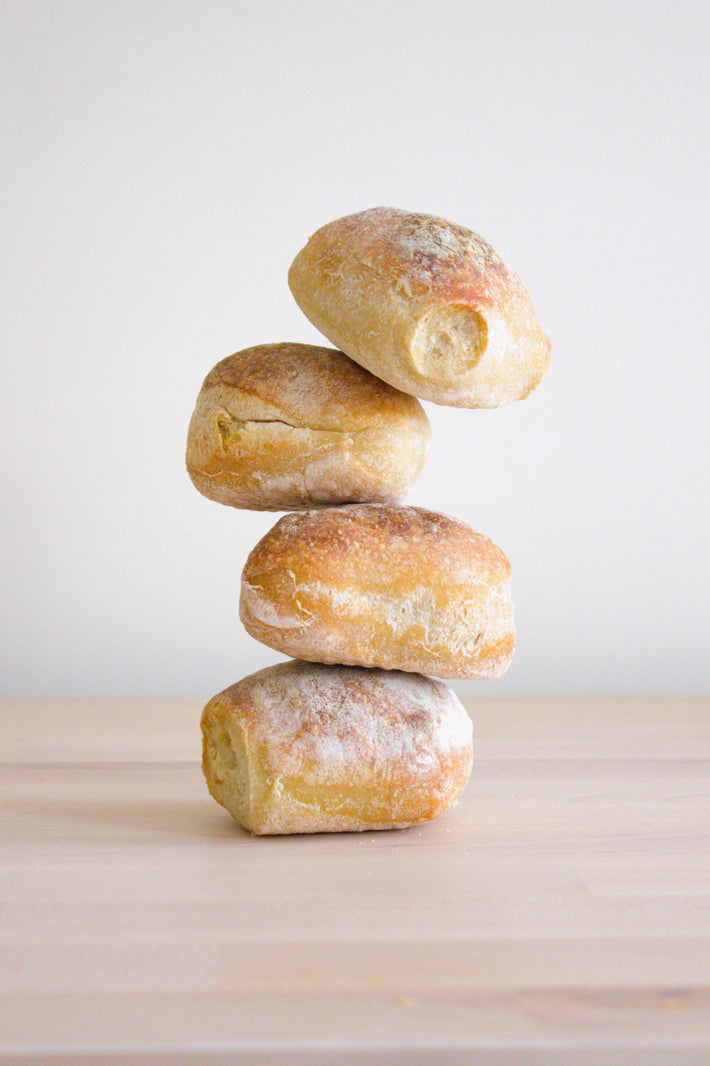 Four stacked sourdough rolls on a wooden surface
