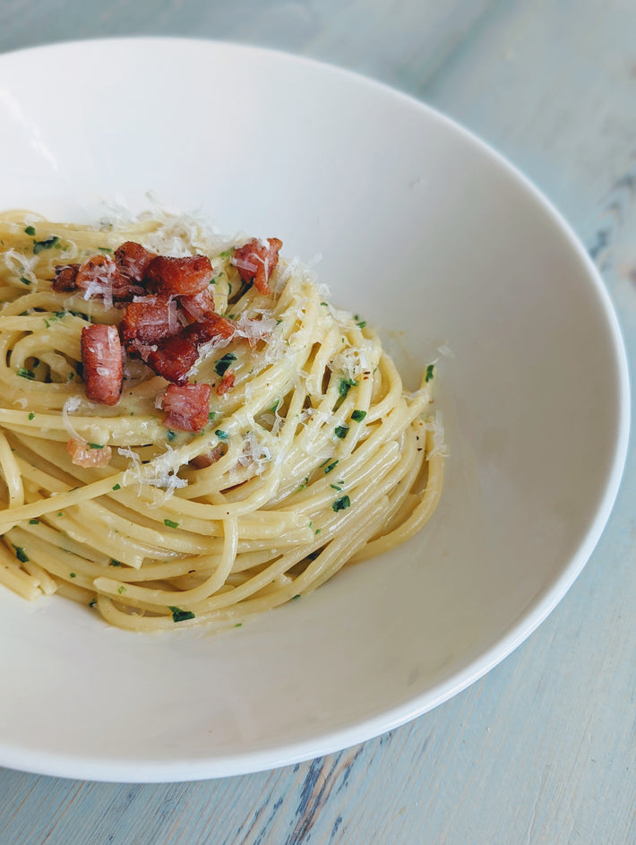 Spaghetti with pancetta and cheese in a white bowl